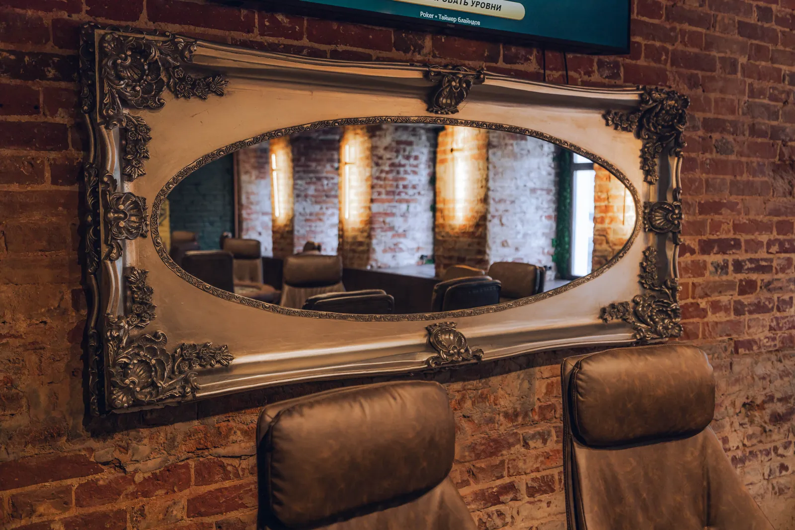 Lounge area with a brick wall, vintage mirror and leather armchairs